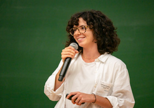 Francesca holding a microphone and talking.